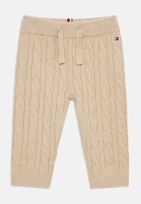 Bežové pletené nohavice s káblovým vzorom, rebrovaný pás so šnúrkou a akcentové logo. Mäkkučká textúra, dizajn so zúženými nohavicami.