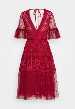 Robe midi en dentelle rouge avec broderie florale, décolleté en V profond, manches évasées transparentes, jupe à volants et fermeture nouée dans le dos.