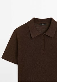 Ruskean neulotun polo-paidan, jossa on kaulus, lyhyet hihat ja neljä nappia. Ribbattu pinta kauluksessa ja hihoissa.