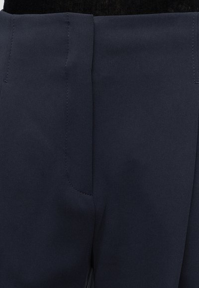 Primer plano de la cintura de pantalones azul marino con costuras visibles y cierre de cremallera.