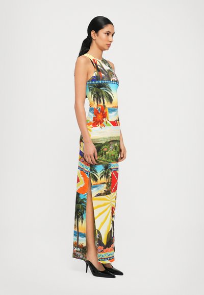 Rochie maxi fără mâneci, colorată, cu modele tropicale, flori vibrante și peisaje pitorești; detalii cu deschidere laterală; asortată cu pantofi cu toc negri.