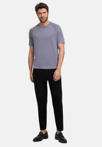 Korte mouwen, lichtpaarse t-shirt van zachte stof, gecombineerd met zwarte broek en zwarte schoenen, met een eenvoudig ontwerp en een aansluitende pasvorm.