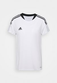 Bílé tričko Adidas s černými akcenty, kulatým výstřihem, krátkými rukávy a třemi černými pruhy na každém rameni. Na hrudi je logo Adidas.