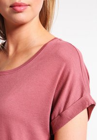 Mauve kortermet T-skjorte laget av myk bomull, med rund hals og oppbrettede ermer, som har en jevn tekstur og minimalistisk design.