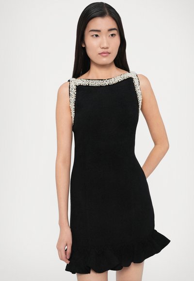 Svart ärmlös klänning med scalloped fåll, prydd med pärlbroderad halsringning och texturerat tyg. Skräddarsydd passform, över knälängd.