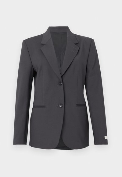 Σκούρο γκρι σακάκι με κομψό σχέδιο, δύο μπροστινά κουμπιά, πέτο και διακριτικές πλαϊνές τσέπες, φτιαγμένο από μαλακό, υφασμάτινο υλικό.