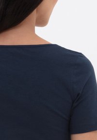 Námořnická modrá košile s krátkým rukávem a kulatým výstřihem, vyrobená z hladké látky, s jednoduchým designem a čistým šitím na okrajích.