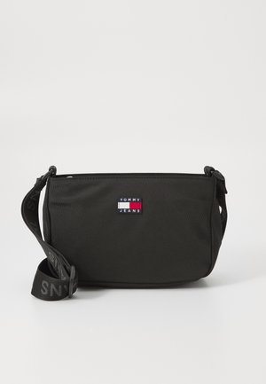 Sac en nylon noir en bandoulière de forme rectangulaire, avec un patch logo et une sangle réglable ornée de texte. Texture lisse.