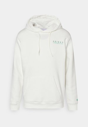 Hvid Adidas-hættetrøje med hætte og forlomme, med lille grønt "Adidas International" tekst på brystet og logo på venstre ærmekant.