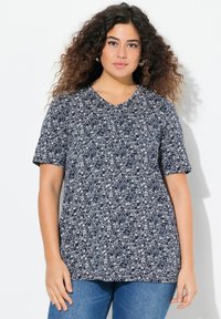 T-shirt a maniche corte blu navy con scollo a V, caratterizzato da un motivo floreale bianco. Tessuto morbido con vestibilità comoda, indossato con jeans blu.