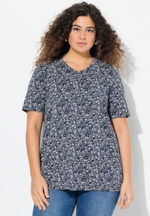 T-shirt a maniche corte blu navy con scollo a V, caratterizzato da un motivo floreale bianco. Tessuto morbido con vestibilità comoda, indossato con jeans blu.