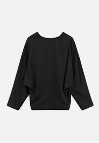 Černý oversized top s širokým krkem a kleslými švy na ramenou, vyrobený z měkké tkaniny s hladkou strukturou a minimem švů.