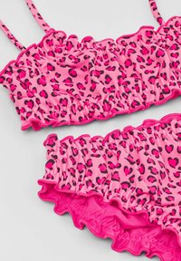 Bikini-Set mit pinkem Leopardenmuster, ausgestattet mit Rüschenkanten und verstellbaren Trägern, gefertigt aus einem dehnbaren, glatten Material.