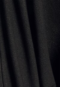 Närbild av svart tyg med diagonalt vävd struktur och subtil glans, som visar mjuka veck och fina trådar.