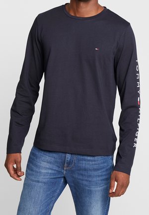 Marineblaues Langarm-T-Shirt aus Baumwolle. Verfügt über einen runden Halsausschnitt und den Schriftzug "TOMMY HILFIGER" entlang des Ärmels. Klassische Passform.