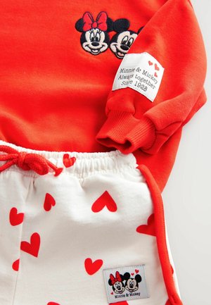 Punane kapuutsiga särk, millel on tikitud Minnie ja Mickey Mouse. Valged püksid punaste südame mustrite ja nööriotsaga. Sildil on kirjas: "Minnie & Mickey."