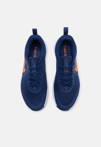 Scarpe sportive in rete blu navy con accenti arancioni, caratterizzate da una tomaia testurizzata, chiusura con lacci e linguetta, completata da un suola bianca.