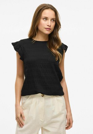 Haut noir texturé avec des manches courtes à volants, présentant des motifs rayés verticaux. Assorti à un pantalon beige clair plissé.
