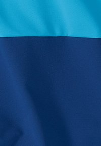 Ύφασμα δύο τόνων με λεία υφή, το πάνω μέρος ανοιχτό μπλε και το κάτω μέρος σκουρό μπλε, εμφανίζοντας απαλά πτυχώσεις.