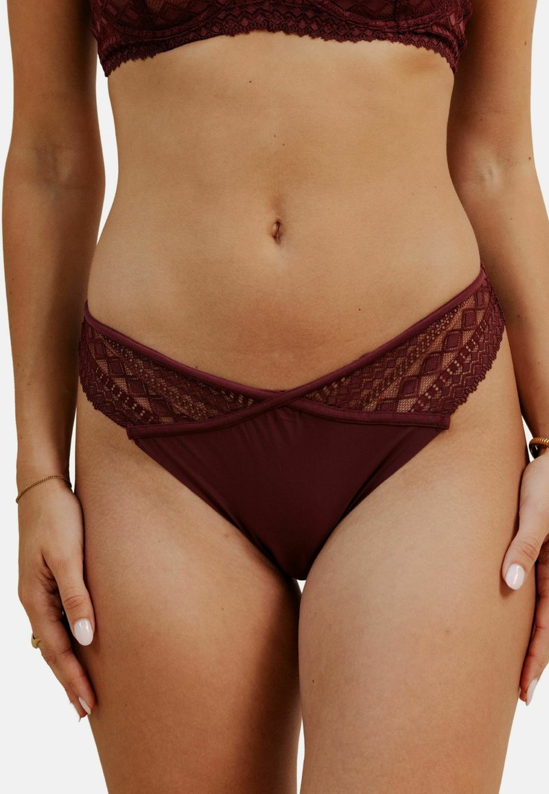 Bas de bikini bordeaux avec dentelle, au design croisé, présentant des motifs en diamant élaborés le long de la ceinture et un tissu lisse.