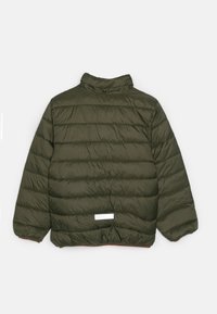 Veste à coussin d'air verte avec une texture matelassée, col haut et fermeture à pression. Présente une étiquette blanche sur l'ourlet arrière et des poignets élastiques.