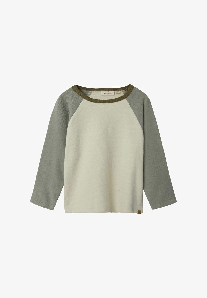 Long-sleeve shirt in light beige with olive green raglan sleeves. Soft fabric, round neckline, and small logo tag at the bottom left.