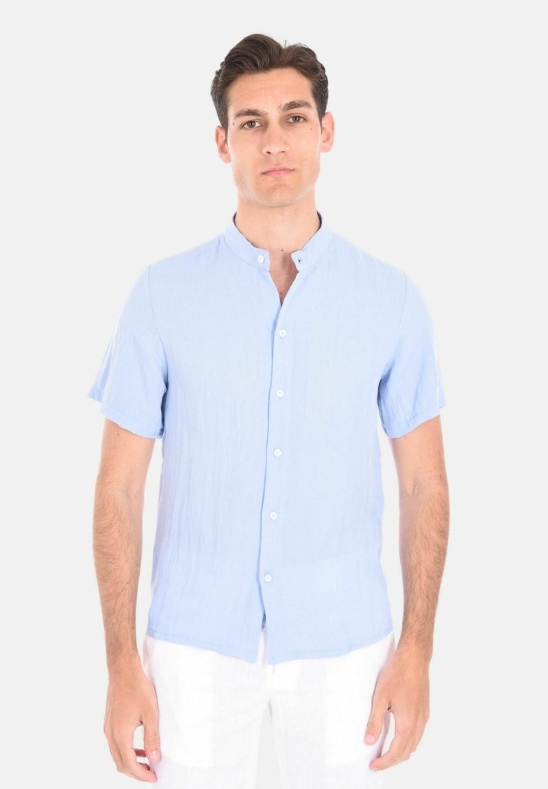 Camicetta azzurro chiaro a maniche corte realizzata in un tessuto texturizzato, con colletto a fascia e chiusura frontale con bottone.