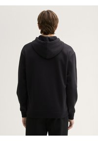 Felpa con cappuccio scura e dalla vestibilità comoda. Presenta polsini e orlo a coste, una texture liscia e dettagli cuciti sulle spalle e sul cappuccio.