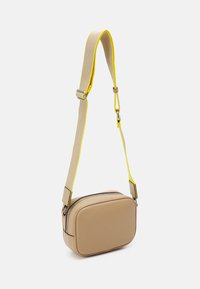 Borsa a tracolla beige con forma rettangolare, texture liscia, tracolla con accenti gialli e chiusura con zip. Design minimalista senza loghi visibili.