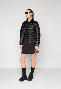 Must värviline sulejope tikandiga, kantud musta pluusi ja seelikuga. Komplekti kuuluvad mustad sokid ja massiivsed mustad kingad.