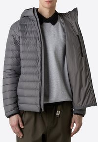 Grå puffjacka med huva, med dragkedja fram, quiltat mönster och en öppen design som avslöjar en grå sweatshirt under.
