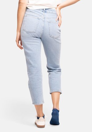 Ljusblå denimjeans med en avslappnad passform, fem fickor och uppvikta benslutar, i kombination med en vit sneaker och marinblå strumpor.