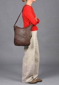 Bruine geweven leren schoudertas met een gestructureerd oppervlak, voorzien van een verstelbare schouderband en een ruime indeling.