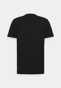 Camiseta negra de manga corta y cuello redondo vista desde la parte de atrás, exhibida sobre un fondo blanco liso.