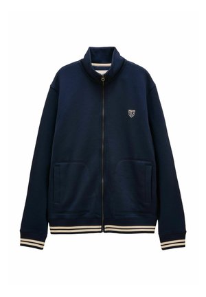Navy blue zip-up jacket with high collar, two front pockets, small white logo on chest, and striped cuffs and hem.