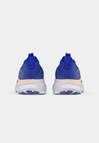 Zapatillas deportivas azules con parte superior de malla, tira en la parte trasera y media suela blanca. Presentan acentos texturizados y una suela exterior con patrón para un mejor agarre.