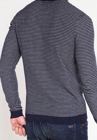 Laivastonsininen ja valkoraidallinen neulepusero, jossa pitkät hihat, resorit hihansuissa ja helmassa. Valmistettu teksturoidusta kankaasta, istuva malli ja korkea kaulus.