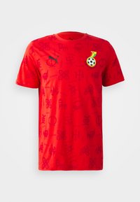 Rød T-shirt med korte ærmer, der har et tonalt grafisk mønster, sort Puma-logo og et emblem i sort/gul/grøn med et fodboldmotiv.