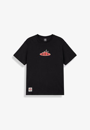 Czarna koszulka z krótkim rękawem z czerwonym owalnym logo i wzorem płomienia na piersi oraz małą białą prostokątną łatką przy dolnym brzegu.