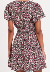 Robe à imprimé floral avec manches courtes bouffantes, taille cintrée et jupe évasée. Présente une base marron avec des fleurs roses, blanches et turquoise.