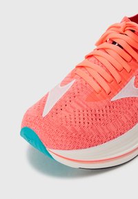 Juoksukengät, joissa on vaaleanpunainen neulospinta, valkoinen Nike-merkki ja turkooseja yksityiskohtia pohjassa. Ominaisuuksiin kuuluu teksturoitu pinta ja tasaiset nauhat.