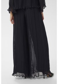 Tengerészkék, pliszírozott, bőszárú nadrág, könnyű, áttetsző anyagból, puha tapintású textúrával. Laza szabású, a földig érő kialakítással.