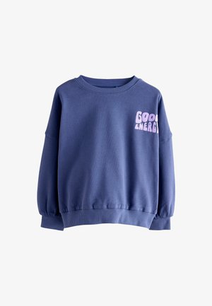 Violetinis džemperis su apvaliu iškirpimu, nuleistomis rankovėmis ir rankogaliais. Priekyje esantis tekstas sako "GERA ENERGIJA" šviesiai rožine spalva. Minkšta tekstūra.