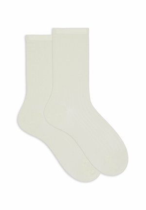Due calze a coste di lunghezza crew di colore bianco sporco disposte piatte, sovrapposte, con punta rinforzata e polsini elasticizzati.