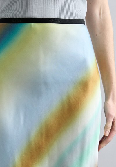 A colorful skirt featuring a gradient design with blue, yellow, and brown tones; a smooth texture; and a black waistband with branding.