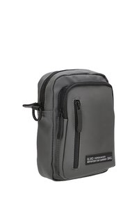 Bolsa de tela gris con dos compartimentos con cremallera, forma rectangular plana y un lazo para sujeción. Presenta una etiqueta de marca en la parte frontal.