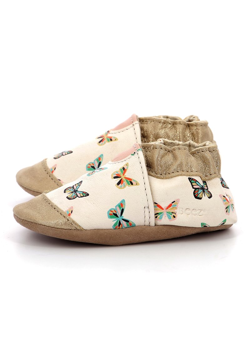 Scarpe per bambini stampate con farfalle in morbido tessuto crema con punta in suede tan e polsino elastico dorato. Design leggero e flessibile.