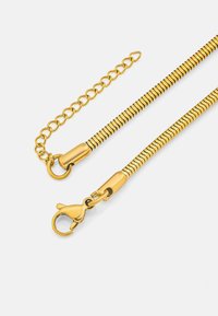 Catena in metallo dorato con un design testurizzato e flessibile; presenta anelli e un moschettone girevole. Finitura liscia con un aspetto lucido.