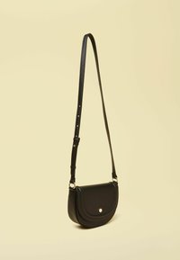 Čierna crossbody kabelka z textúrovanej kože s oblým klopou, nastaviteľným popruhom a zlatými kovaniami na zapínanie.