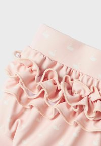 Rosa volangtyg med ett mönster av vita svanar. Mjuk textur med elastisk midja. Accentuerad med kontrasterande sömnad längs volangens kant.